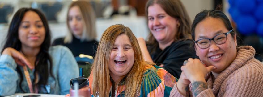 Image of people laughing at an event on campus. Main focus is a women laughing in the middle.